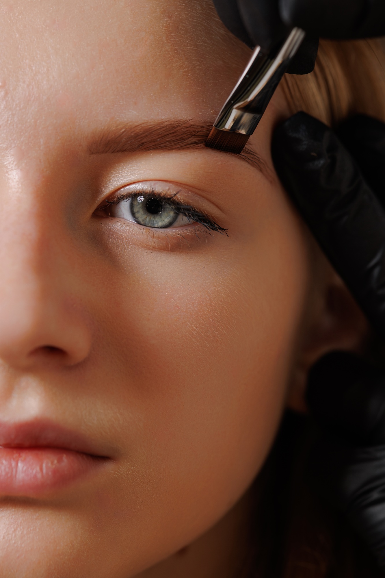 Master eyebrow artist makes eyebrow correction to a girl in a beauty salon, close-up of eyebrow care