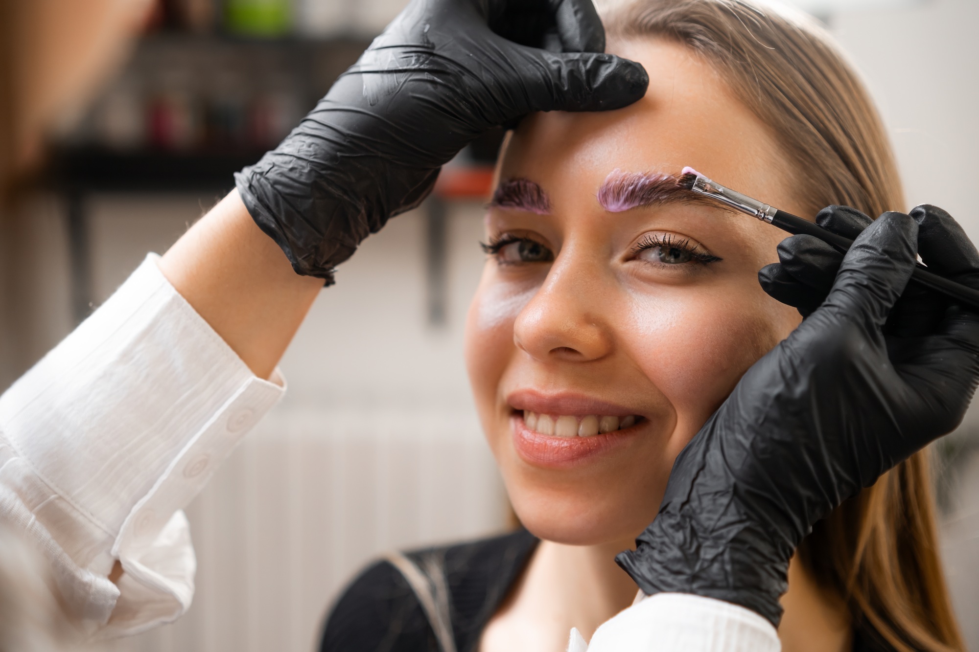 Portrait of young woman during procedure of lamination of eyebrows.